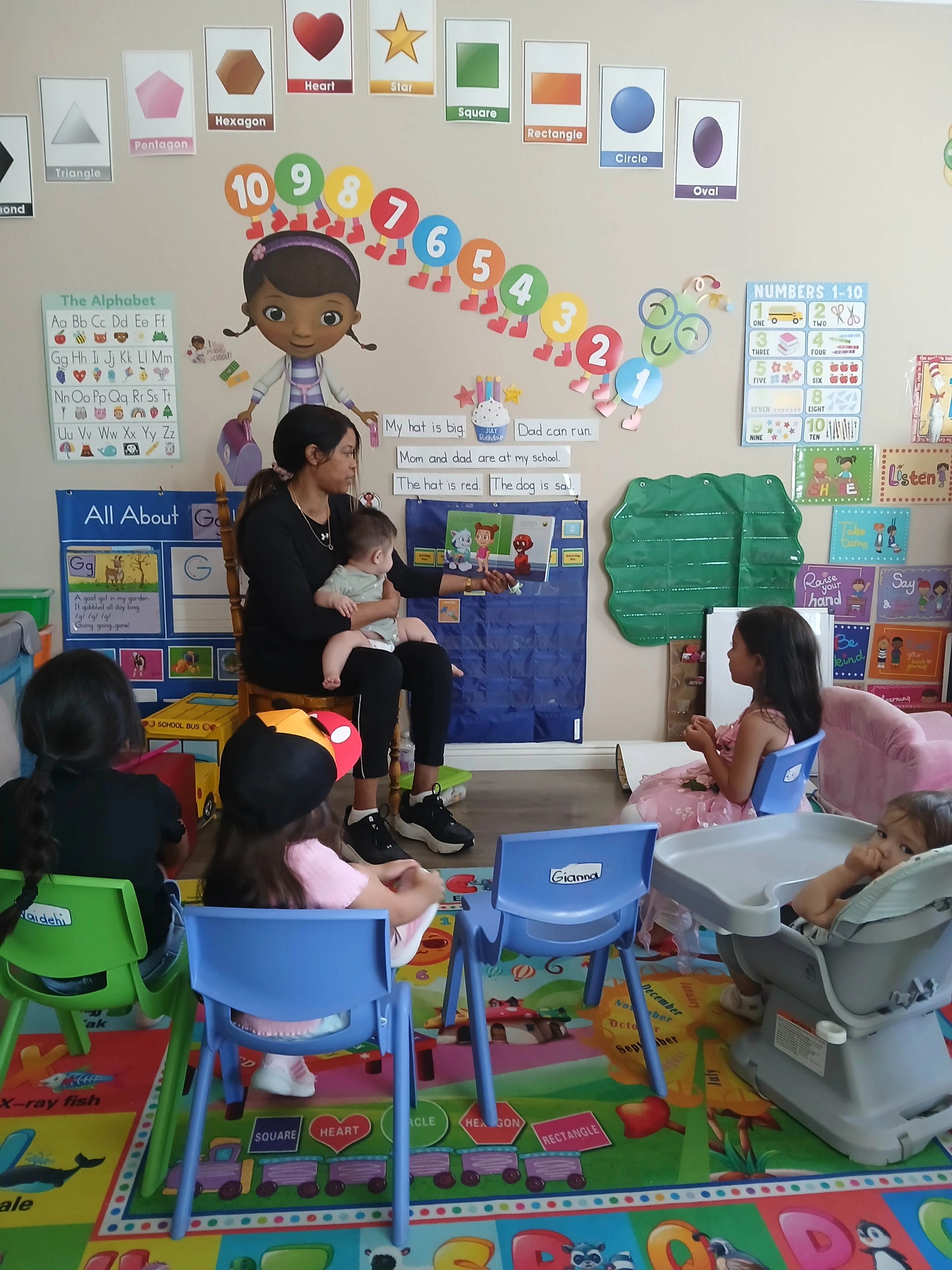 Teacher reading a story to children with a baby in her lap